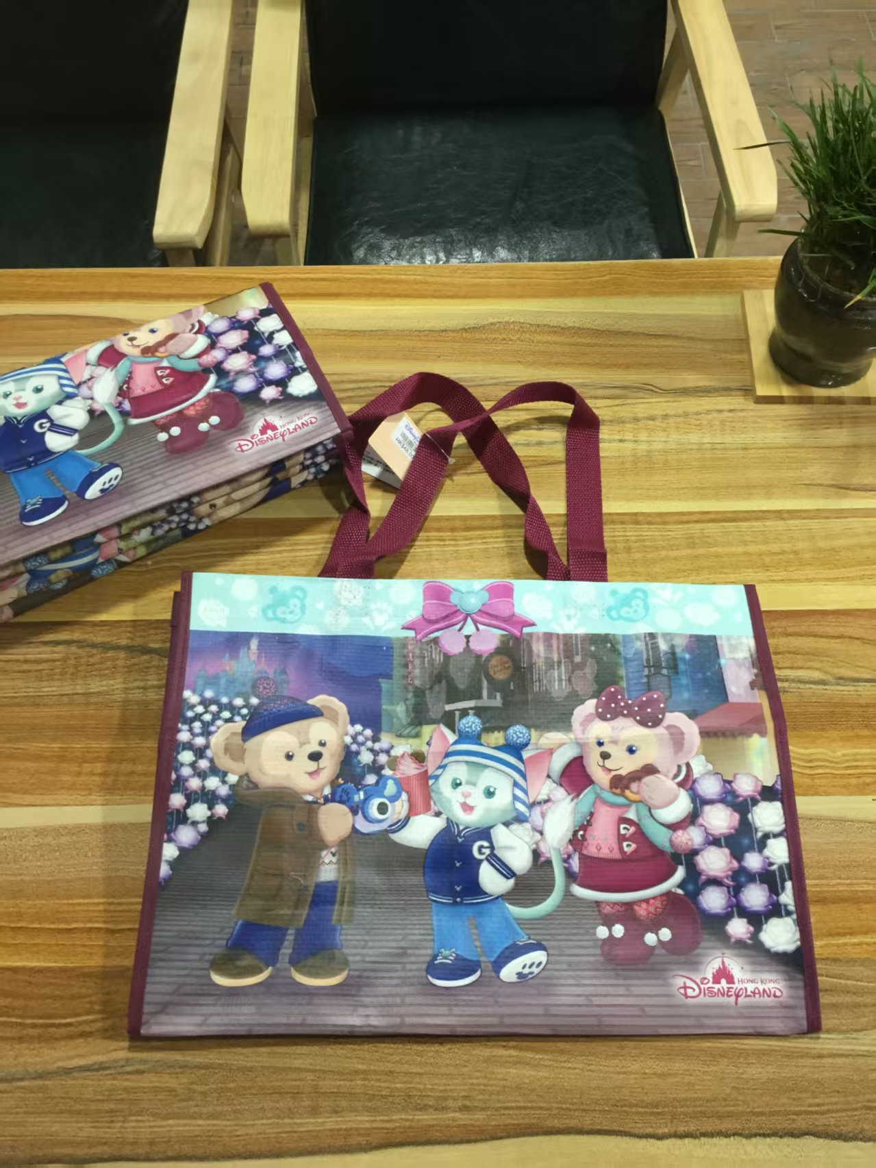 Non-woven souvenir bag with cartoon bear print and maroon handles