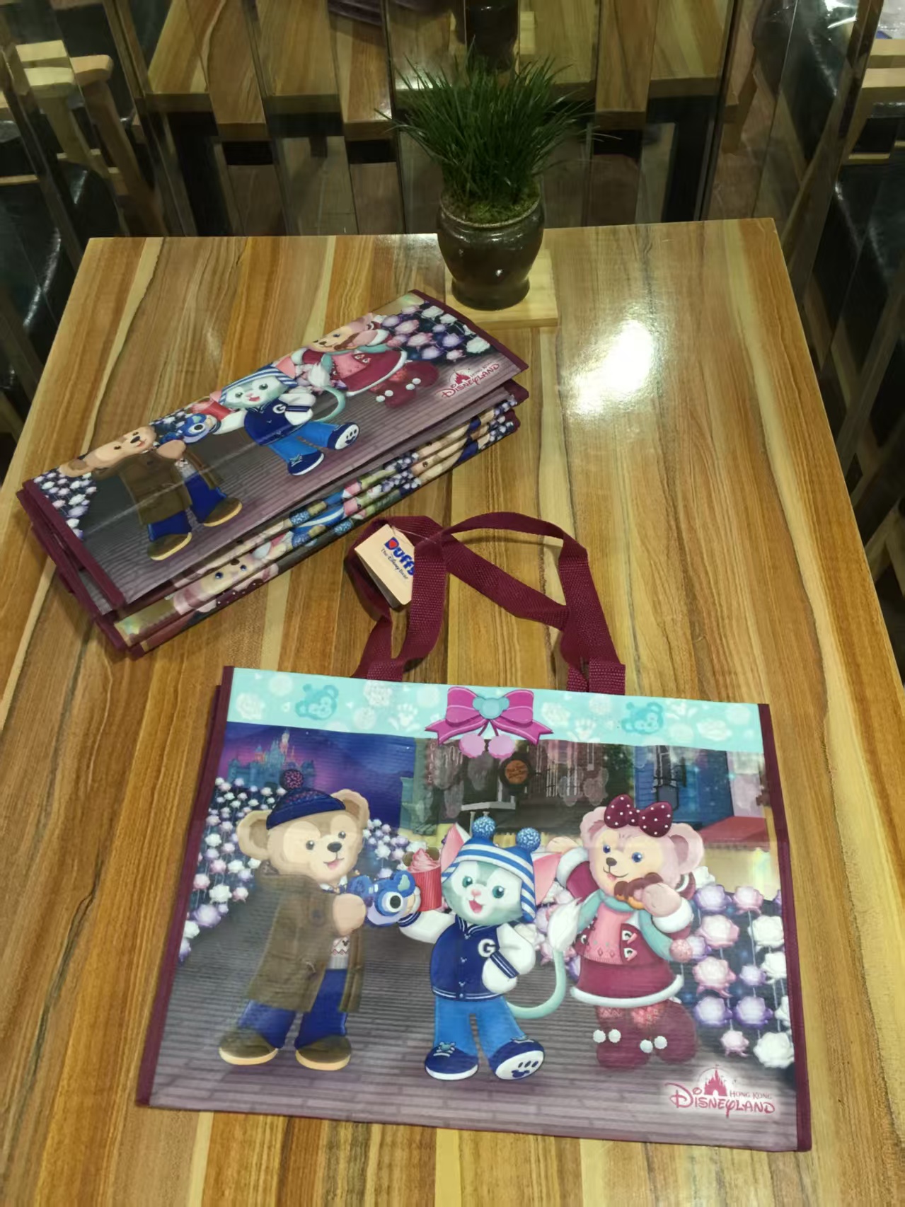Stack of cartoon print non-woven souvenir bags on a wooden table