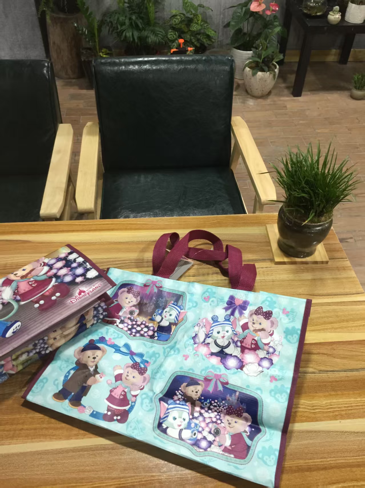 Non-woven souvenir bags with teal cartoon print on a wooden table
